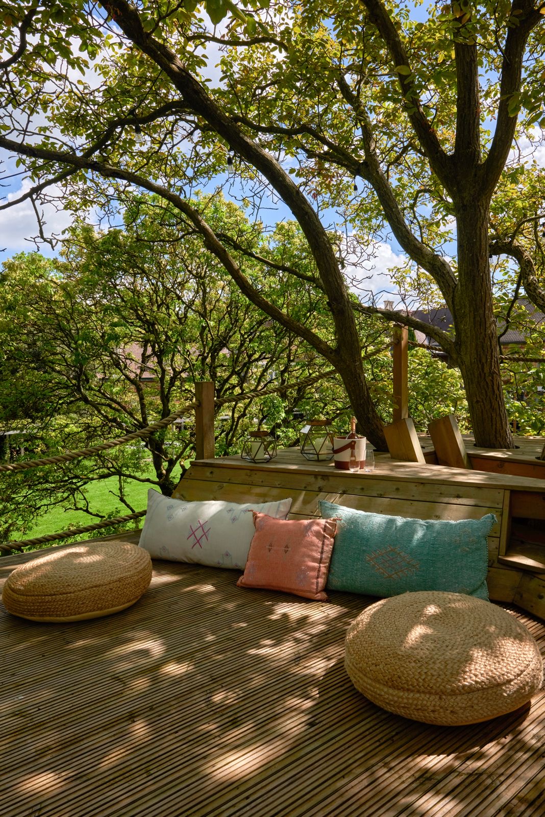 A wooden deck with floor cushions beneath the trees