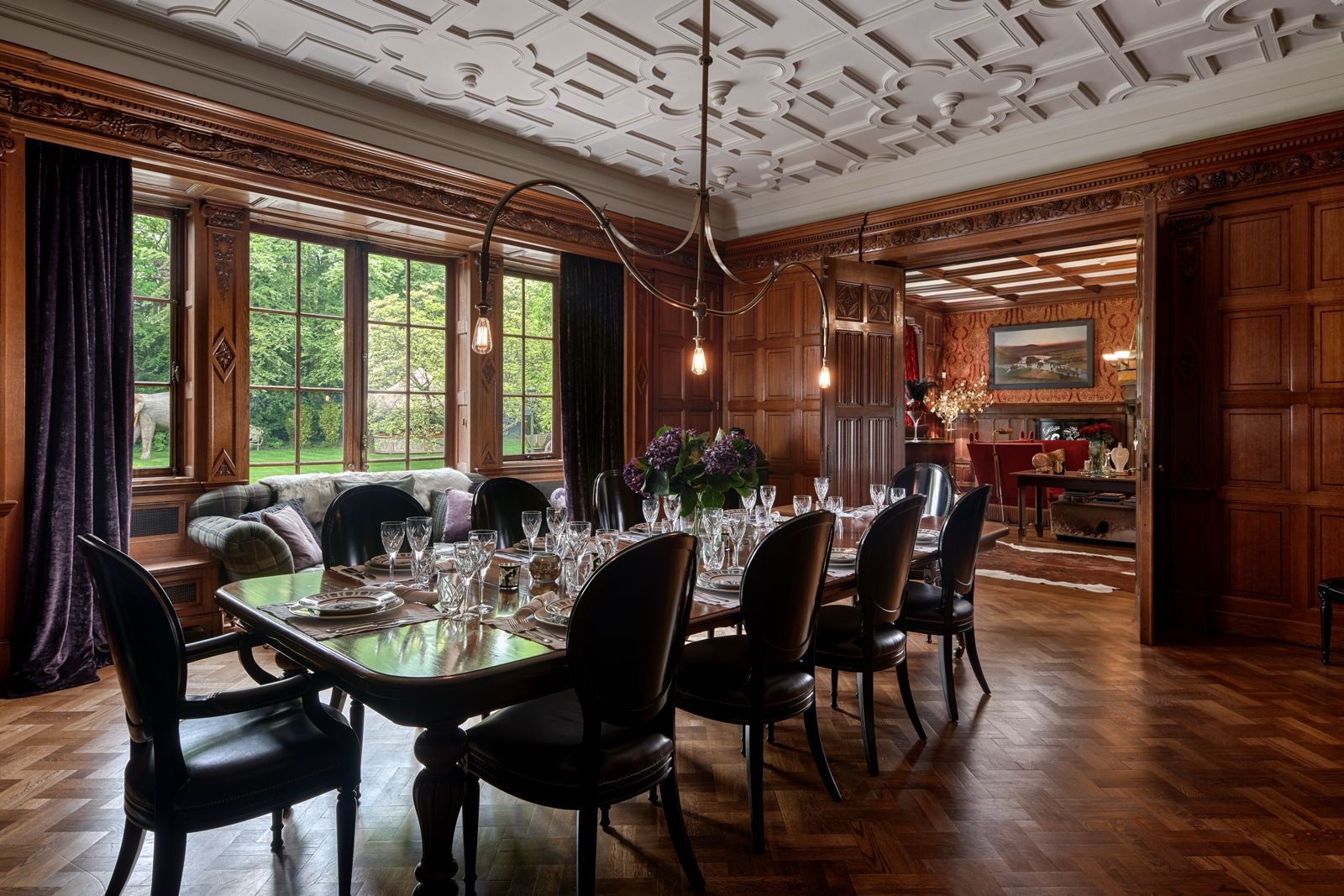 The oak-panelled dining room with a long table beneath an ornate ceiling