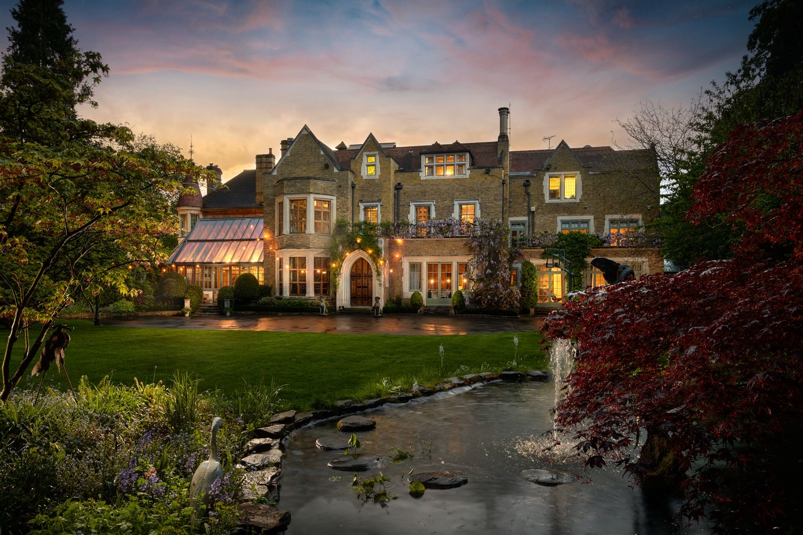 The home lit up at dusk beyond the pond